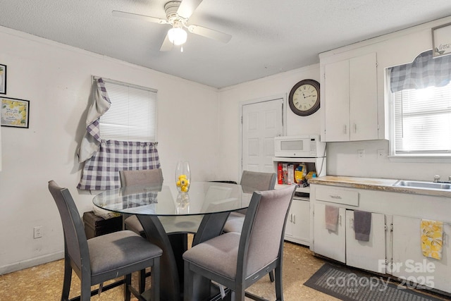 dining area featuring a textured ceiling, ceiling fan, and sink