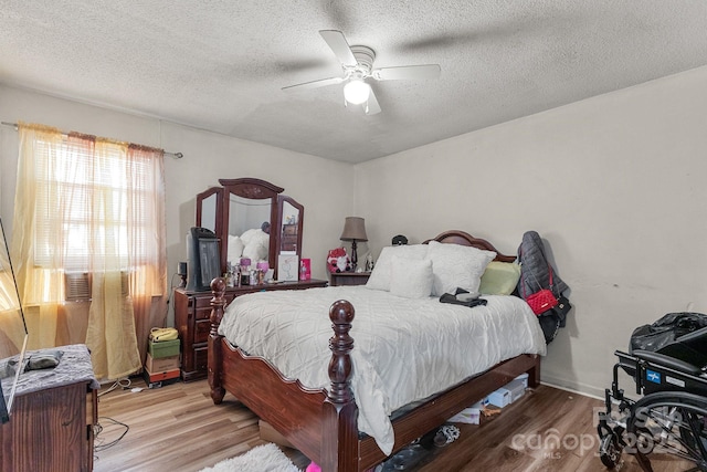 bedroom featuring ceiling fan, light hardwood / wood-style flooring, and a textured ceiling