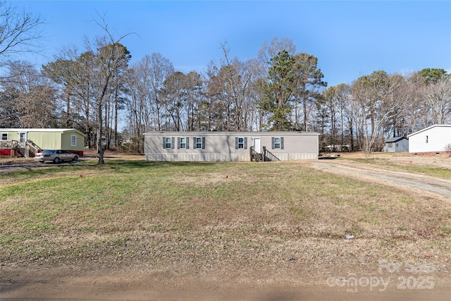 manufactured / mobile home featuring dirt driveway and a front lawn