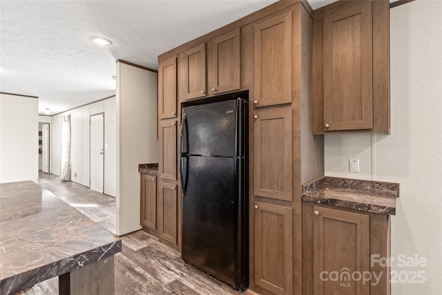 kitchen featuring dark countertops, freestanding refrigerator, and brown cabinets