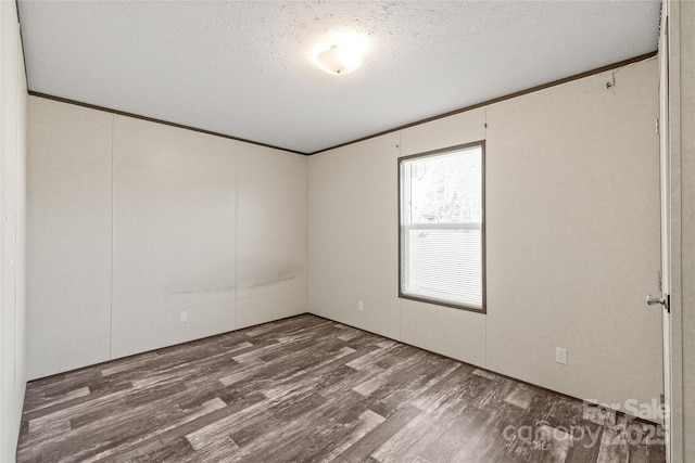 unfurnished room featuring dark wood-style floors, a textured ceiling, and crown molding