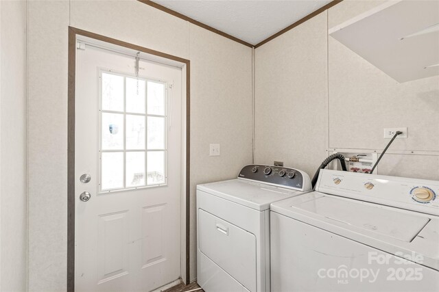 washroom with ornamental molding, washing machine and dryer, and laundry area