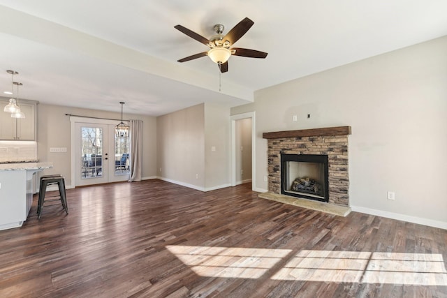 unfurnished living room with ceiling fan, french doors, dark wood-type flooring, and a fireplace