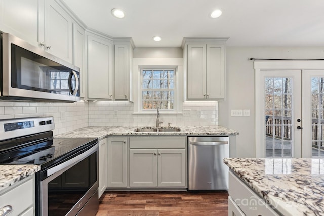 kitchen featuring light stone countertops, appliances with stainless steel finishes, french doors, sink, and backsplash