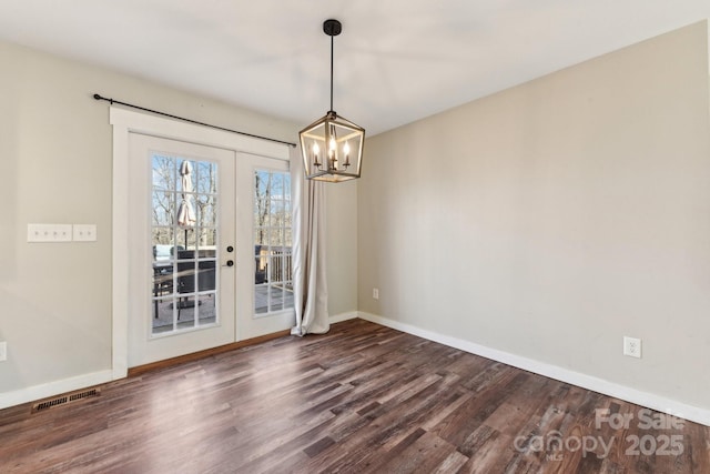 spare room featuring dark wood-type flooring, a chandelier, and french doors