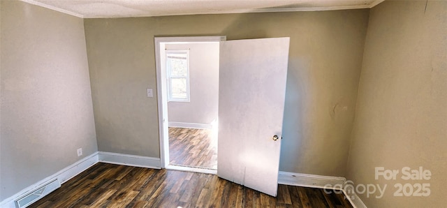 empty room featuring ornamental molding and dark wood-type flooring