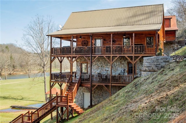 rear view of property with a yard and a deck with water view