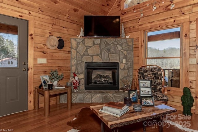 living room with a fireplace, wood-type flooring, a healthy amount of sunlight, and wood walls