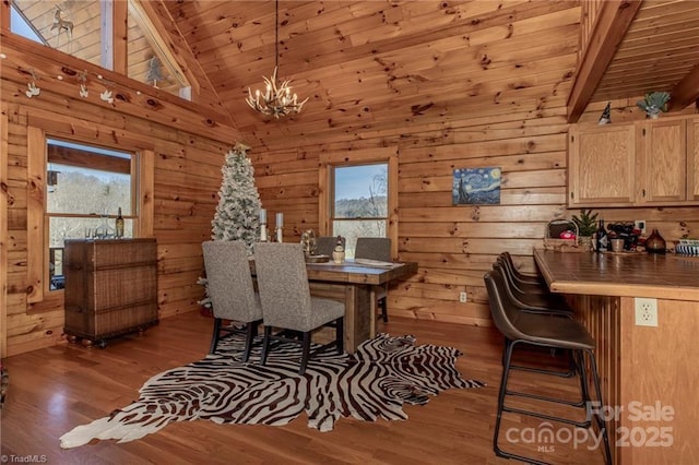 dining space featuring wooden ceiling, an inviting chandelier, high vaulted ceiling, hardwood / wood-style floors, and wooden walls