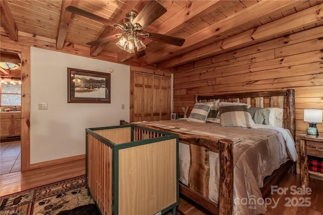 bedroom with wood walls, sink, ceiling fan, beam ceiling, and wood ceiling