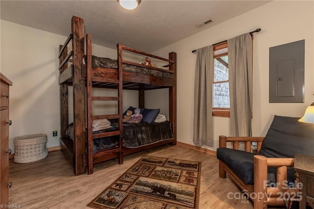 bedroom featuring electric panel and light hardwood / wood-style flooring