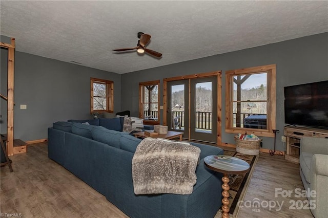 living room with hardwood / wood-style floors, ceiling fan, and a textured ceiling