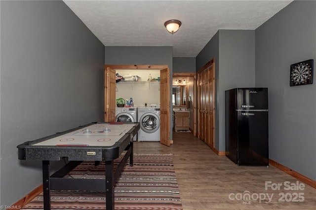 playroom featuring hardwood / wood-style floors, a textured ceiling, and separate washer and dryer