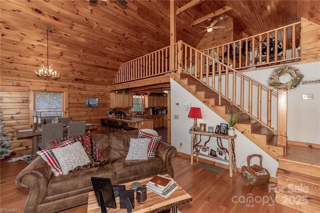 living room with wood ceiling, ceiling fan with notable chandelier, wood-type flooring, high vaulted ceiling, and wood walls