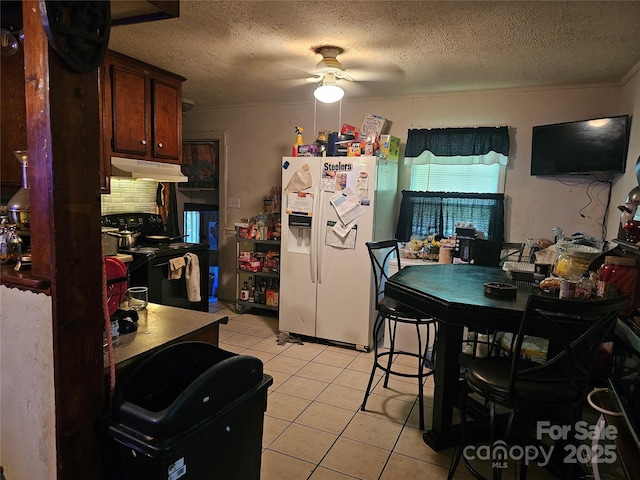 kitchen featuring white refrigerator with ice dispenser, ceiling fan, light tile patterned floors, a textured ceiling, and black range with electric cooktop