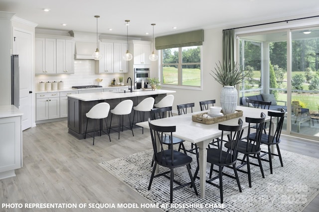 dining room with light wood-type flooring, crown molding, and sink