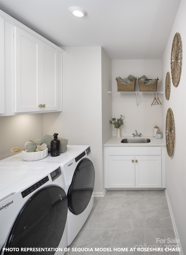 clothes washing area with cabinets, washing machine and dryer, light tile patterned floors, and sink