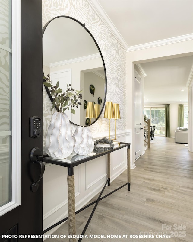 hall featuring a decorative wall, crown molding, wainscoting, light wood-type flooring, and wallpapered walls