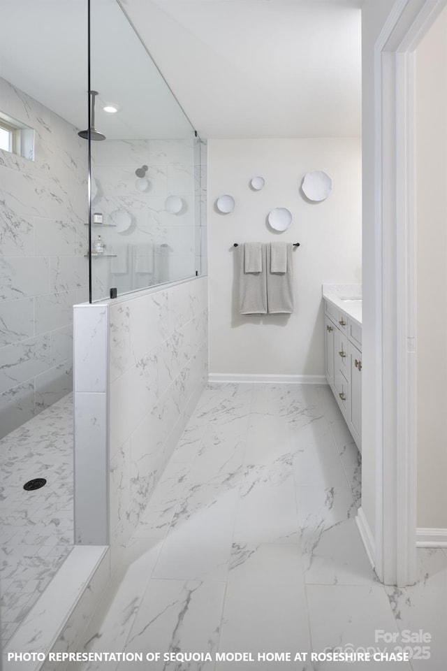 bathroom featuring marble finish floor, a marble finish shower, vanity, and baseboards