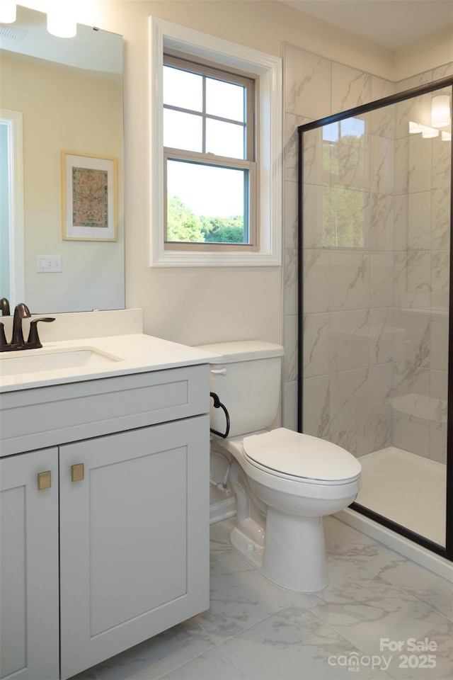 bathroom featuring marble finish floor, a shower stall, toilet, and vanity