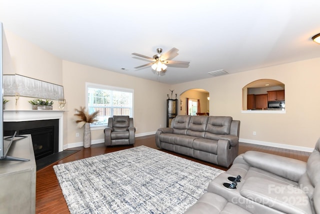 living room with ceiling fan and dark wood-type flooring