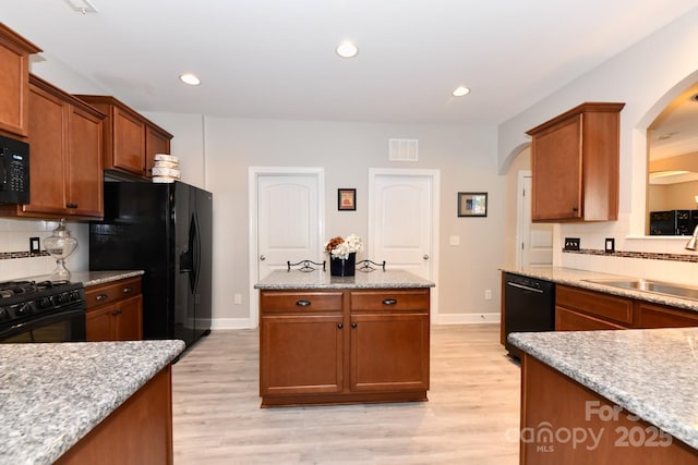 kitchen featuring sink, light wood-type flooring, tasteful backsplash, and black appliances