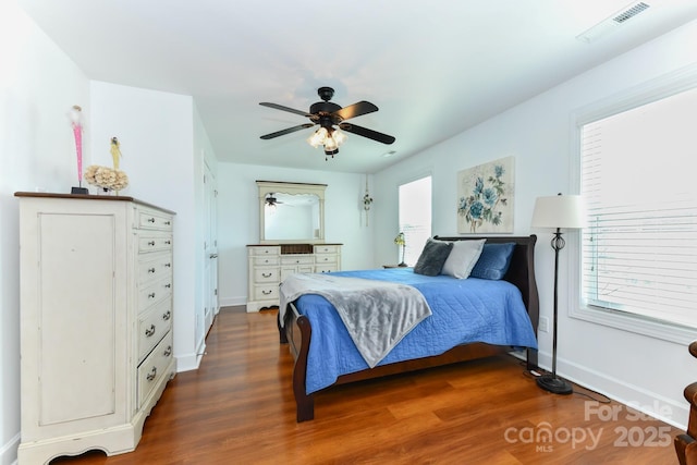 bedroom with ceiling fan, dark hardwood / wood-style flooring, and multiple windows