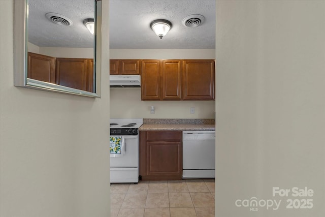 kitchen featuring light tile patterned floors, a textured ceiling, and white appliances