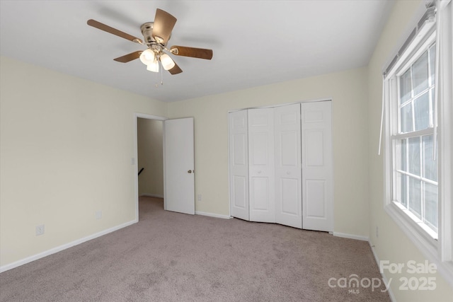 unfurnished bedroom featuring ceiling fan, a closet, and light carpet