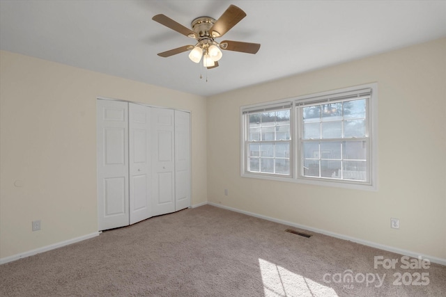 unfurnished bedroom featuring light carpet, ceiling fan, and a closet