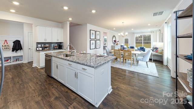 kitchen with light stone counters, an island with sink, white cabinetry, and sink