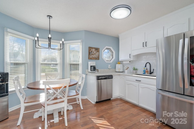 kitchen featuring decorative light fixtures, sink, white cabinetry, and stainless steel appliances