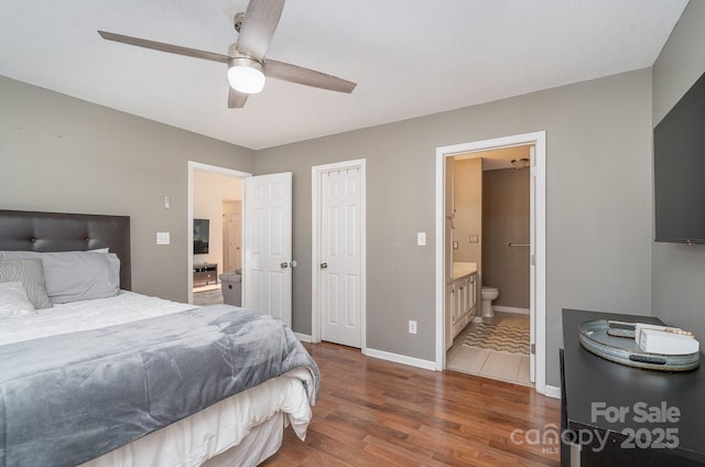 bedroom featuring ceiling fan, dark wood-type flooring, and ensuite bath