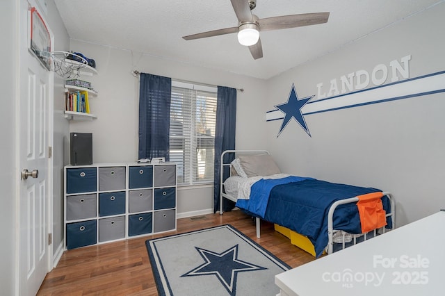 bedroom with a textured ceiling, dark hardwood / wood-style flooring, and ceiling fan