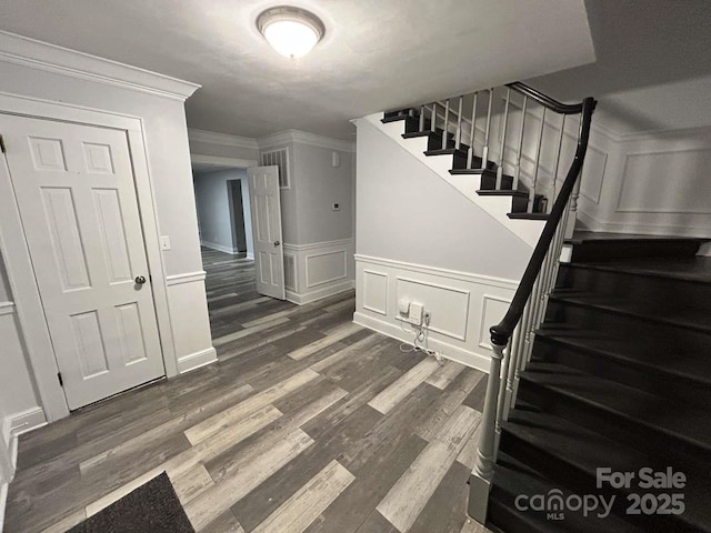 stairway with wood-type flooring and ornamental molding