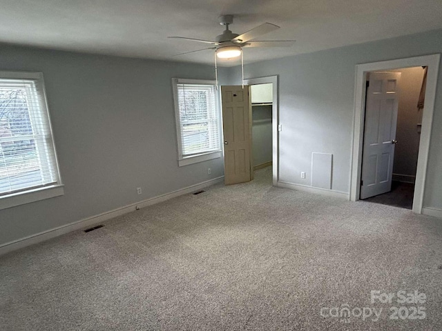 unfurnished bedroom featuring ceiling fan, a closet, carpet floors, and a spacious closet