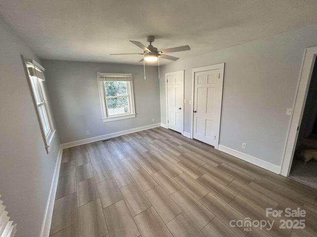 unfurnished bedroom featuring light hardwood / wood-style flooring, ceiling fan, and multiple closets