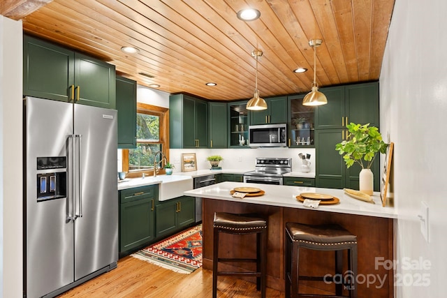 kitchen with wooden ceiling, hanging light fixtures, appliances with stainless steel finishes, and green cabinetry