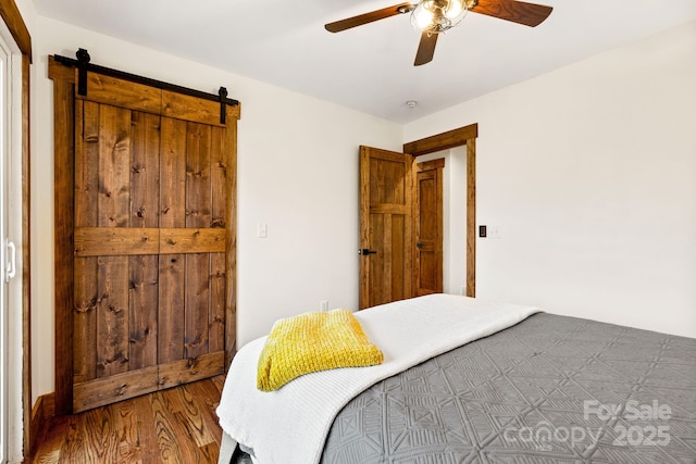 bedroom with a barn door, hardwood / wood-style flooring, and ceiling fan