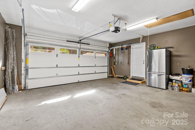 garage with stainless steel fridge and a garage door opener