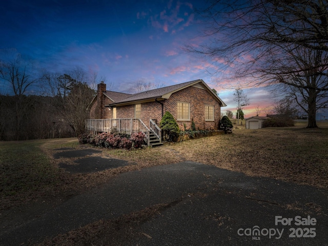 property exterior at dusk with an outbuilding, a garage, and a deck