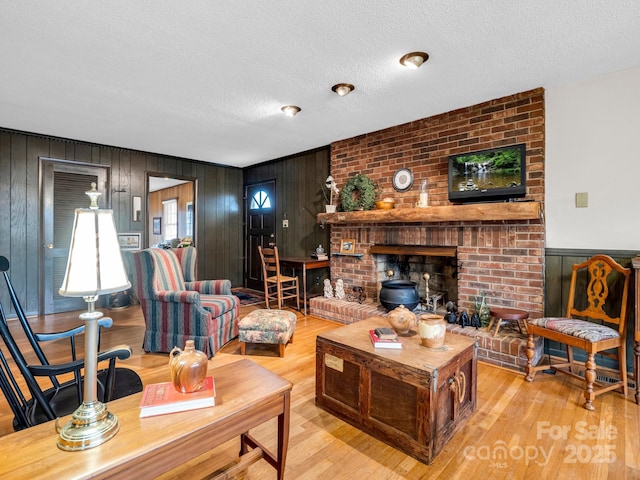 living room with a fireplace, light hardwood / wood-style flooring, and a textured ceiling