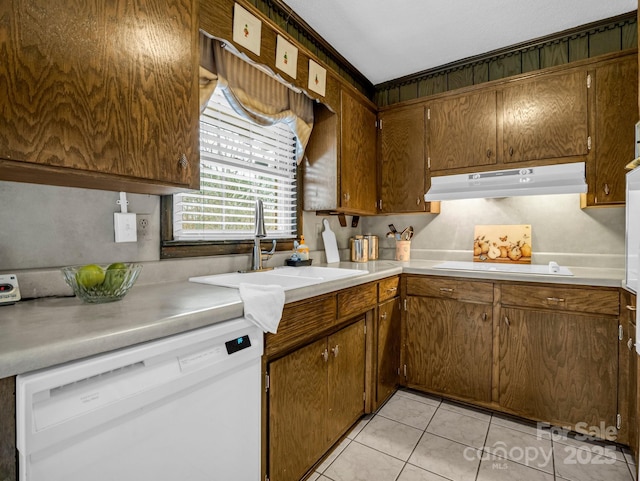 kitchen with white dishwasher, sink, light tile patterned floors, and cooktop