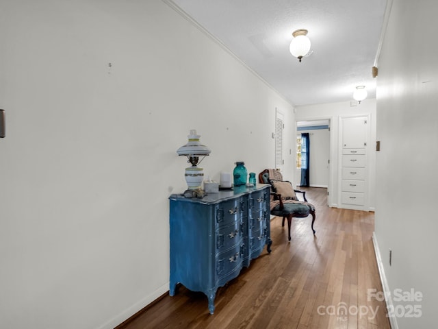 corridor with ornamental molding and hardwood / wood-style floors