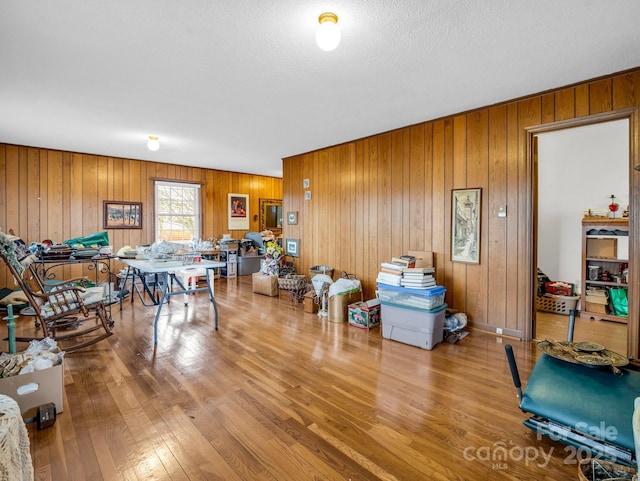 recreation room featuring hardwood / wood-style floors, a textured ceiling, and wood walls