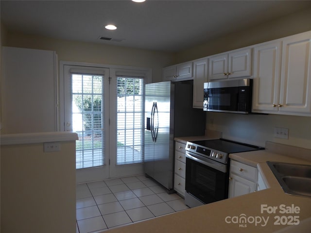 kitchen with white cabinets, appliances with stainless steel finishes, sink, and light tile patterned floors