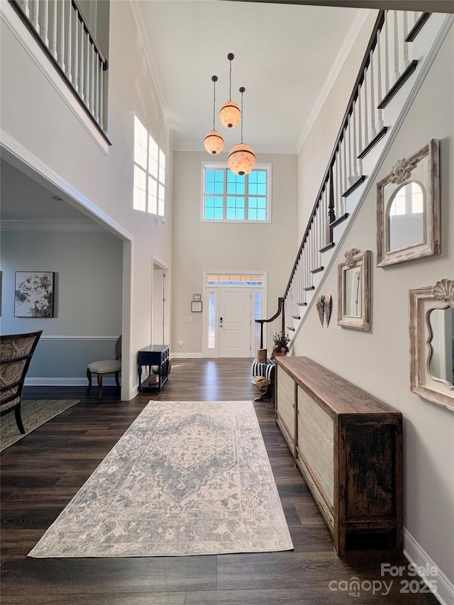 entryway with crown molding, dark wood-type flooring, and a high ceiling