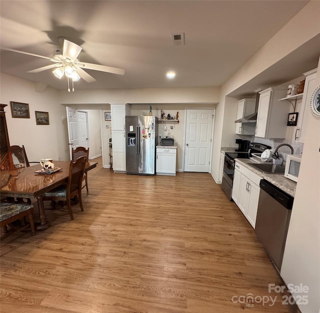 kitchen with white cabinets, ceiling fan, light wood-type flooring, and appliances with stainless steel finishes