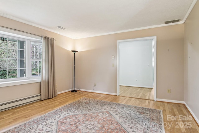 spare room featuring wood-type flooring, crown molding, and baseboard heating