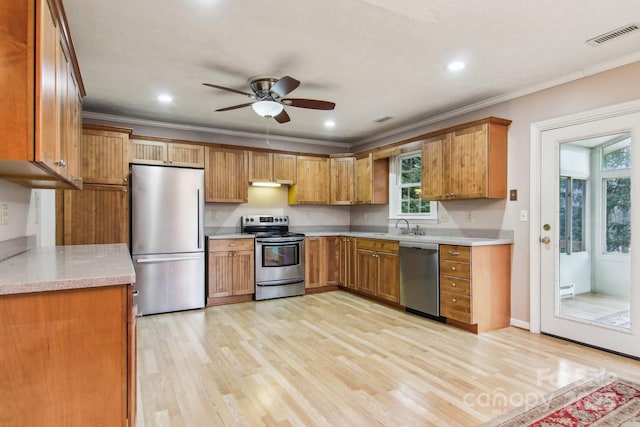 kitchen featuring ceiling fan, sink, stainless steel appliances, crown molding, and light wood-type flooring